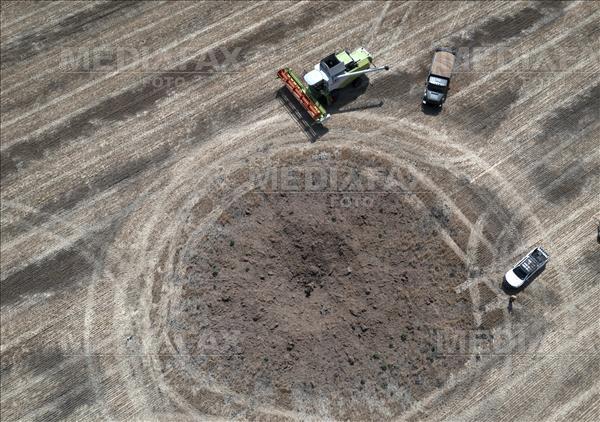 A crater left by a Russian rocket attack is seen as a farmer collects harvest in a field, ten kilometres away from the frontline where fierce battle is ongoing... Foto: AP/Efrem Lukatsky.